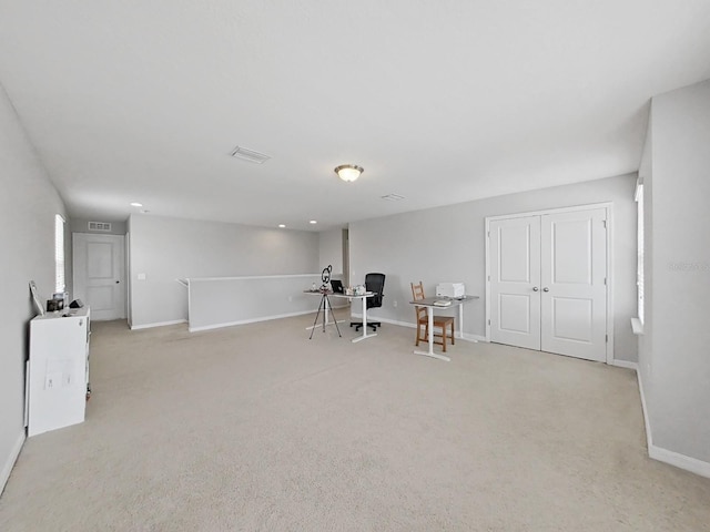 interior space with baseboards, visible vents, and light colored carpet