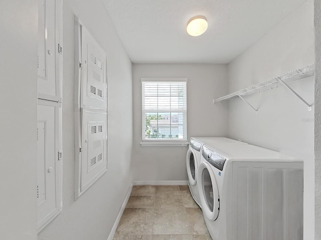 clothes washing area featuring washing machine and dryer, laundry area, and baseboards