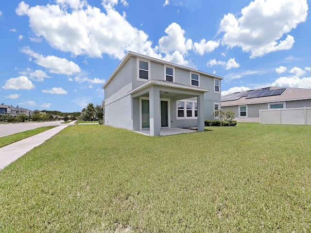 rear view of property with solar panels and a lawn