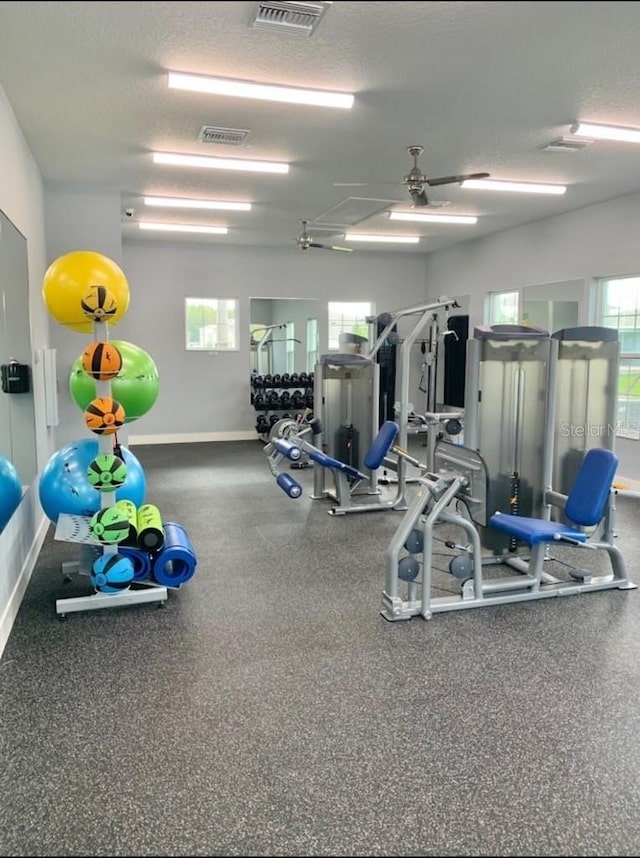 exercise room with baseboards, visible vents, and a textured ceiling