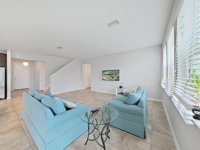 living room with visible vents, stairway, baseboards, and light tile patterned floors