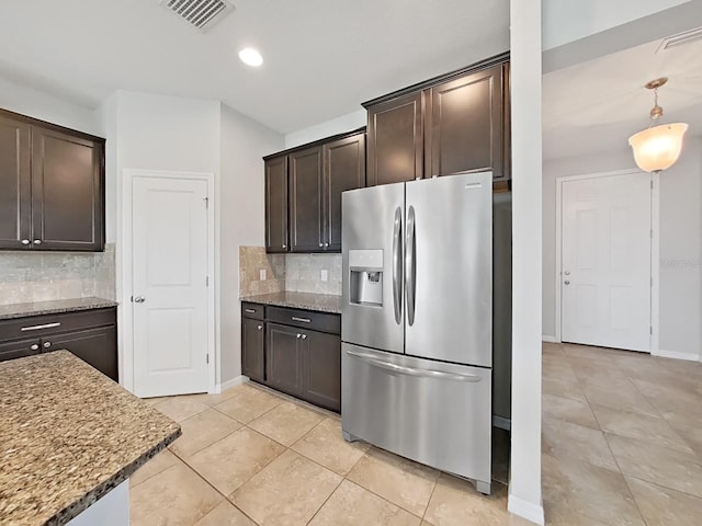 kitchen with dark stone countertops, visible vents, dark brown cabinetry, and stainless steel fridge with ice dispenser