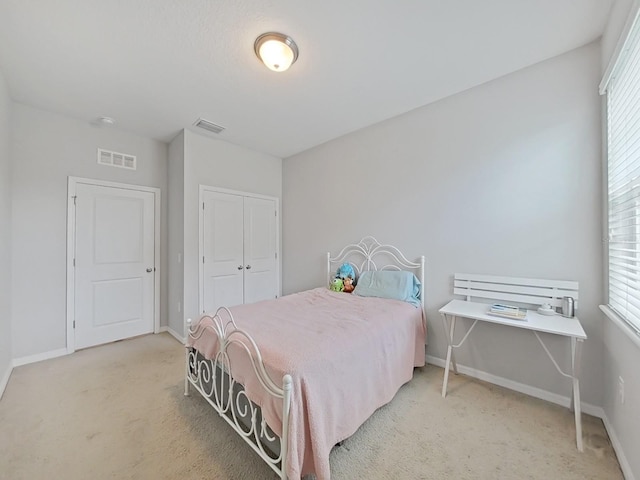 bedroom with light carpet, a closet, visible vents, and baseboards