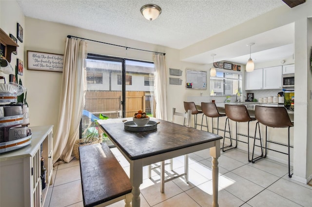 dining area with light tile patterned flooring, a textured ceiling, and a wealth of natural light