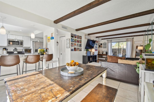 tiled dining area with a textured ceiling and beam ceiling