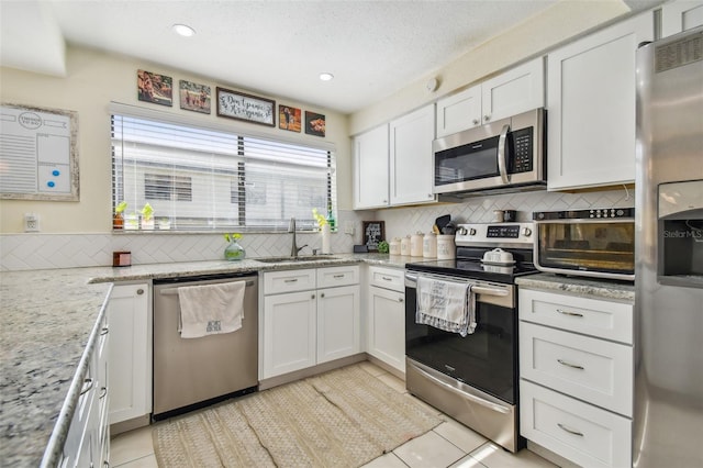 kitchen featuring appliances with stainless steel finishes, tasteful backsplash, white cabinets, and light tile patterned floors