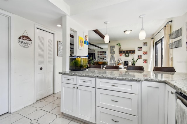 kitchen featuring light tile patterned flooring, white cabinetry, dishwasher, light stone countertops, and hanging light fixtures