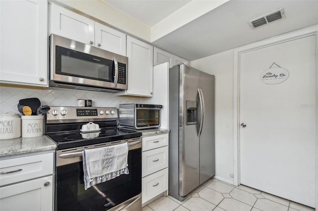 kitchen with appliances with stainless steel finishes, white cabinetry, tasteful backsplash, and light tile patterned flooring