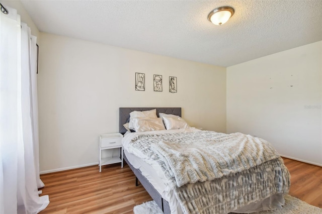 bedroom with light hardwood / wood-style floors and a textured ceiling