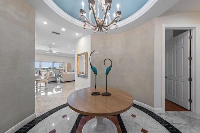 corridor featuring crown molding, a raised ceiling, and a chandelier