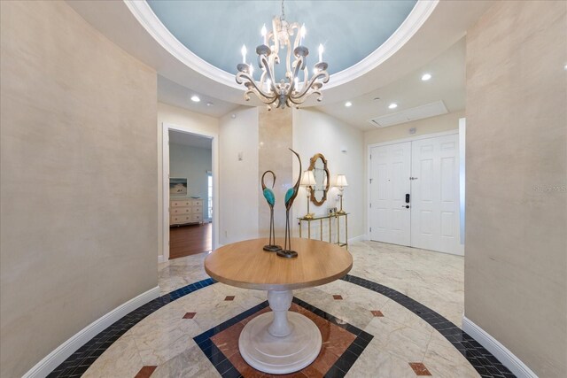 entrance foyer with crown molding, a notable chandelier, and a tray ceiling