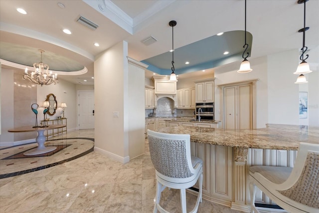 kitchen with pendant lighting, a kitchen breakfast bar, light stone counters, cream cabinets, and ornamental molding