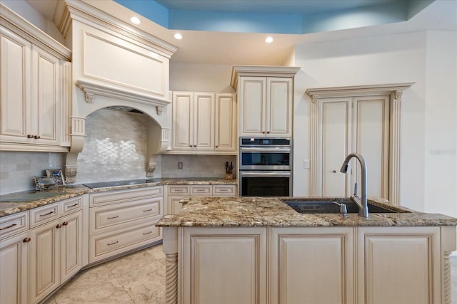 kitchen with sink, decorative backsplash, double oven, and cream cabinetry