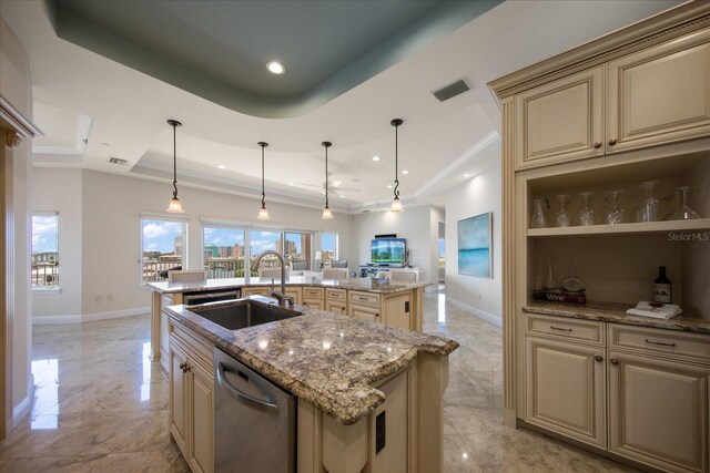 kitchen featuring sink, stainless steel dishwasher, a tray ceiling, an island with sink, and pendant lighting