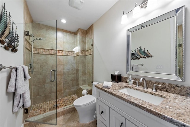 bathroom featuring vanity, a shower with door, and toilet