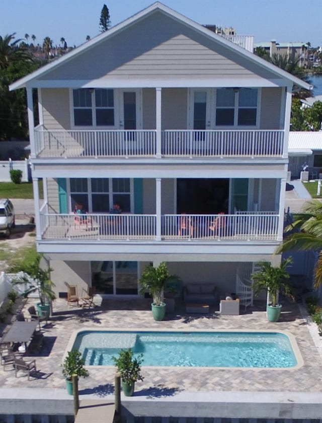 rear view of property with a balcony, a patio area, and an outdoor hangout area