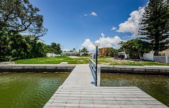 dock area with a lawn and a water view