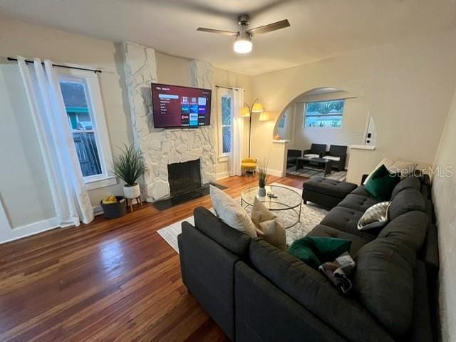 living room featuring ceiling fan, a fireplace, and dark hardwood / wood-style flooring