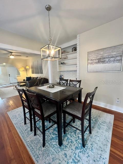 dining space featuring ceiling fan with notable chandelier and wood-type flooring