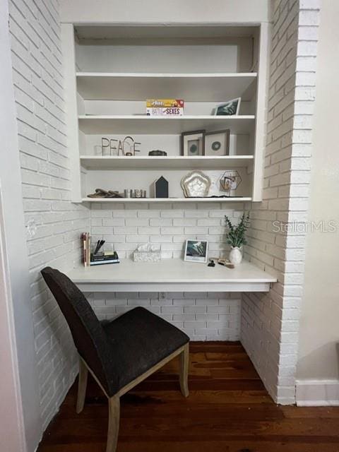 bar featuring dark hardwood / wood-style flooring and brick wall