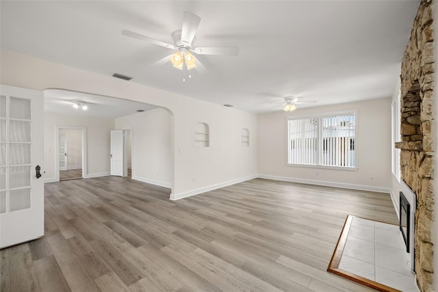 unfurnished living room with a fireplace, ceiling fan, and light hardwood / wood-style floors