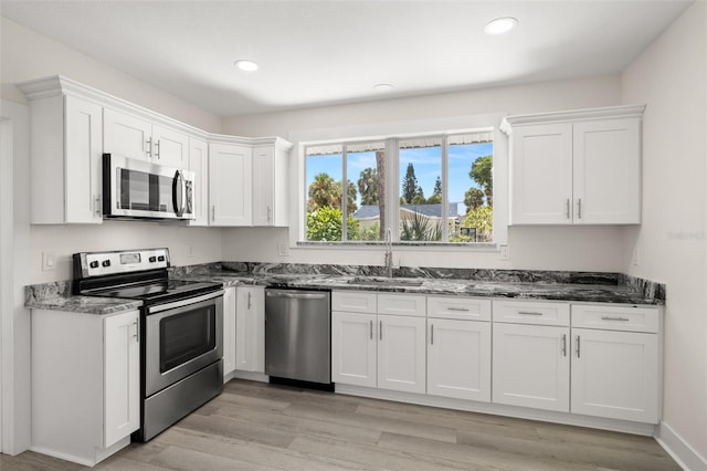 kitchen with white cabinets, light wood-type flooring, appliances with stainless steel finishes, and sink