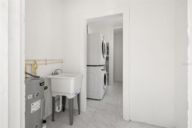 laundry area featuring electric water heater, stacked washer / drying machine, and light tile patterned floors