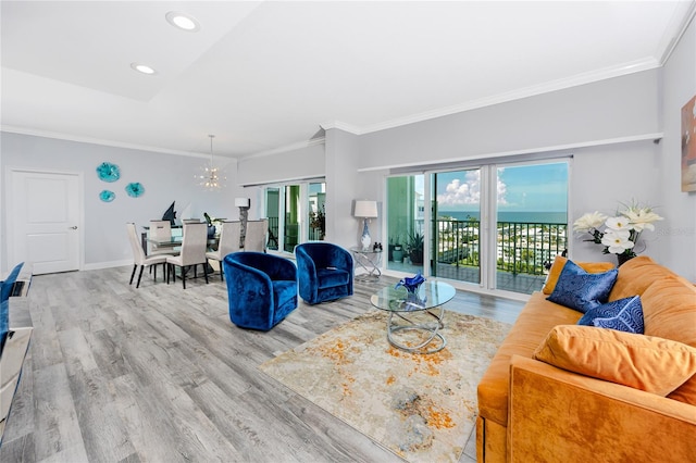 living room with a water view, crown molding, hardwood / wood-style floors, and a chandelier