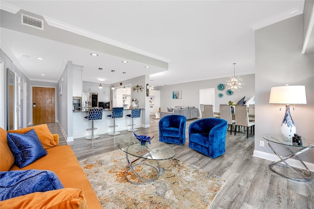 living room featuring a chandelier, crown molding, and light hardwood / wood-style floors