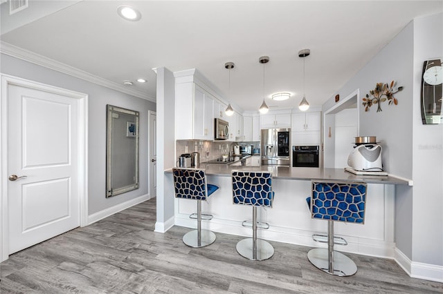 kitchen with stainless steel appliances, kitchen peninsula, white cabinets, and light hardwood / wood-style floors