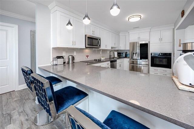 kitchen featuring appliances with stainless steel finishes, tasteful backsplash, light stone counters, light hardwood / wood-style floors, and decorative light fixtures