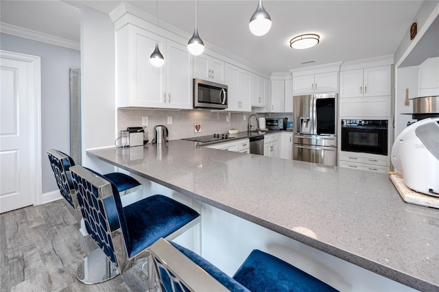 kitchen with decorative backsplash, ornamental molding, wood finished floors, stainless steel appliances, and white cabinetry