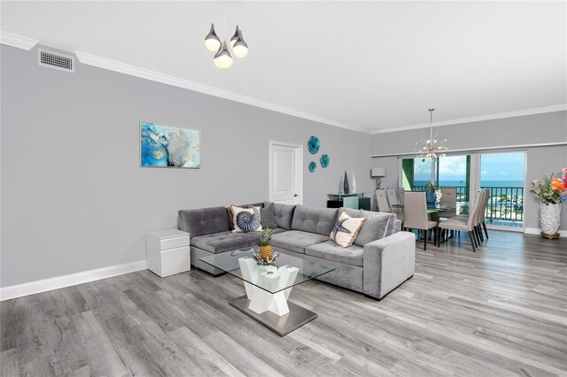 living room featuring ornamental molding, a water view, hardwood / wood-style flooring, and a chandelier