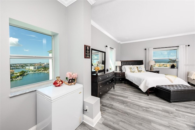 bedroom featuring a water view, fridge, crown molding, and light wood-type flooring