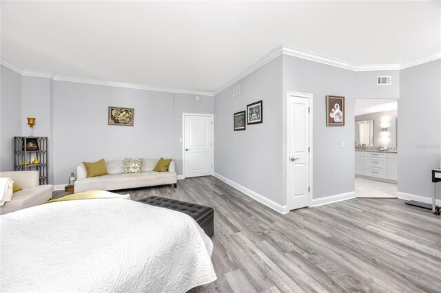 bedroom with light hardwood / wood-style floors, ensuite bath, and crown molding