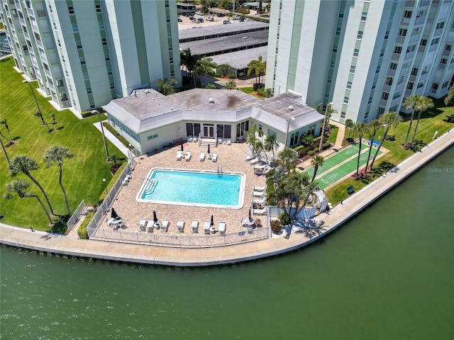 pool featuring a water view, a patio area, and a lawn