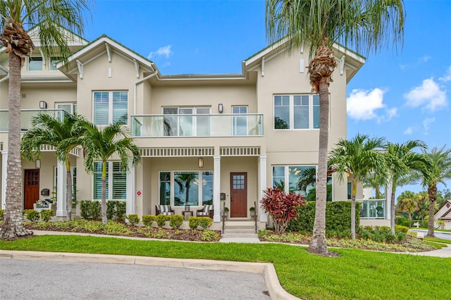 view of front of home with a front lawn, a balcony, and covered porch