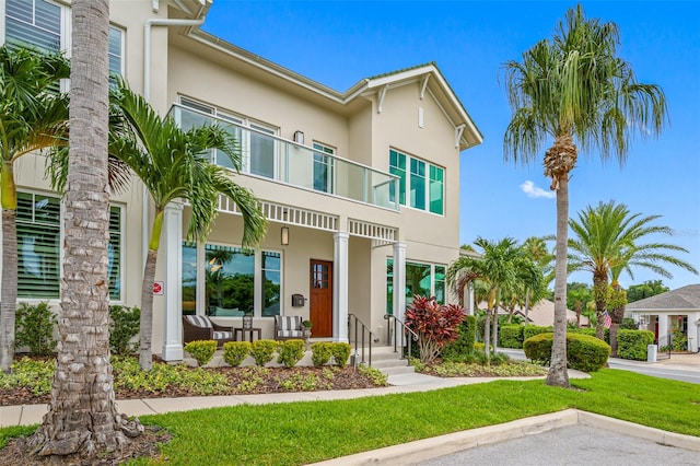 view of front of house featuring a front lawn, a balcony, and a porch