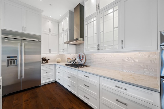 kitchen featuring stainless steel appliances, tasteful backsplash, light stone countertops, white cabinets, and wall chimney exhaust hood