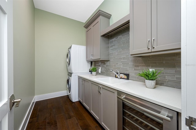 interior space with wine cooler, stacked washer / drying machine, sink, tasteful backsplash, and gray cabinets