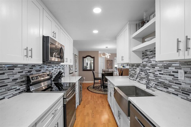 kitchen featuring white cabinets, hanging light fixtures, sink, and appliances with stainless steel finishes