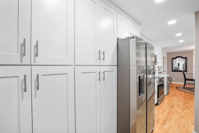 kitchen with appliances with stainless steel finishes, light hardwood / wood-style flooring, and white cabinetry