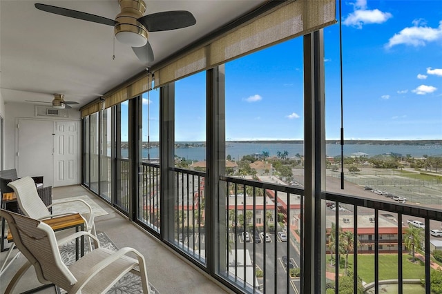 sunroom with ceiling fan, a water view, and plenty of natural light