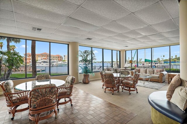 sunroom with a paneled ceiling and a water view