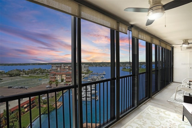 unfurnished sunroom with ceiling fan and a water view