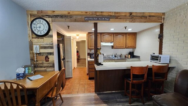 kitchen featuring light tile patterned floors, a textured ceiling, decorative backsplash, kitchen peninsula, and beamed ceiling