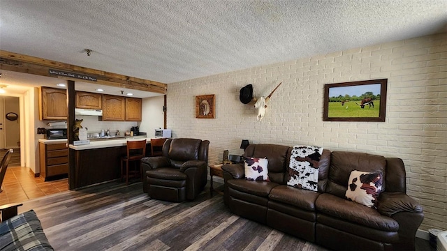 living room with brick wall, dark hardwood / wood-style flooring, and a textured ceiling