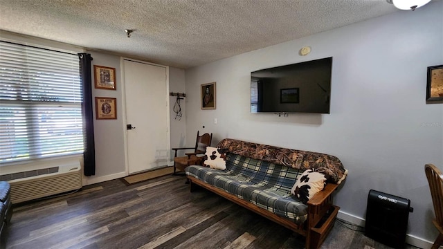 living room featuring dark wood-type flooring, an AC wall unit, and a textured ceiling