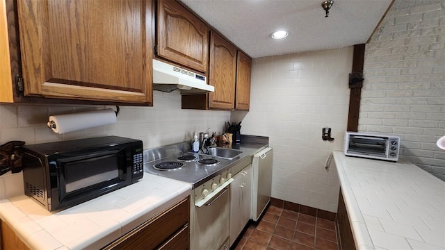 kitchen with dark tile patterned floors, dishwasher, sink, and tile counters