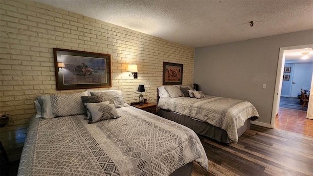 bedroom with brick wall, wood-type flooring, and a textured ceiling